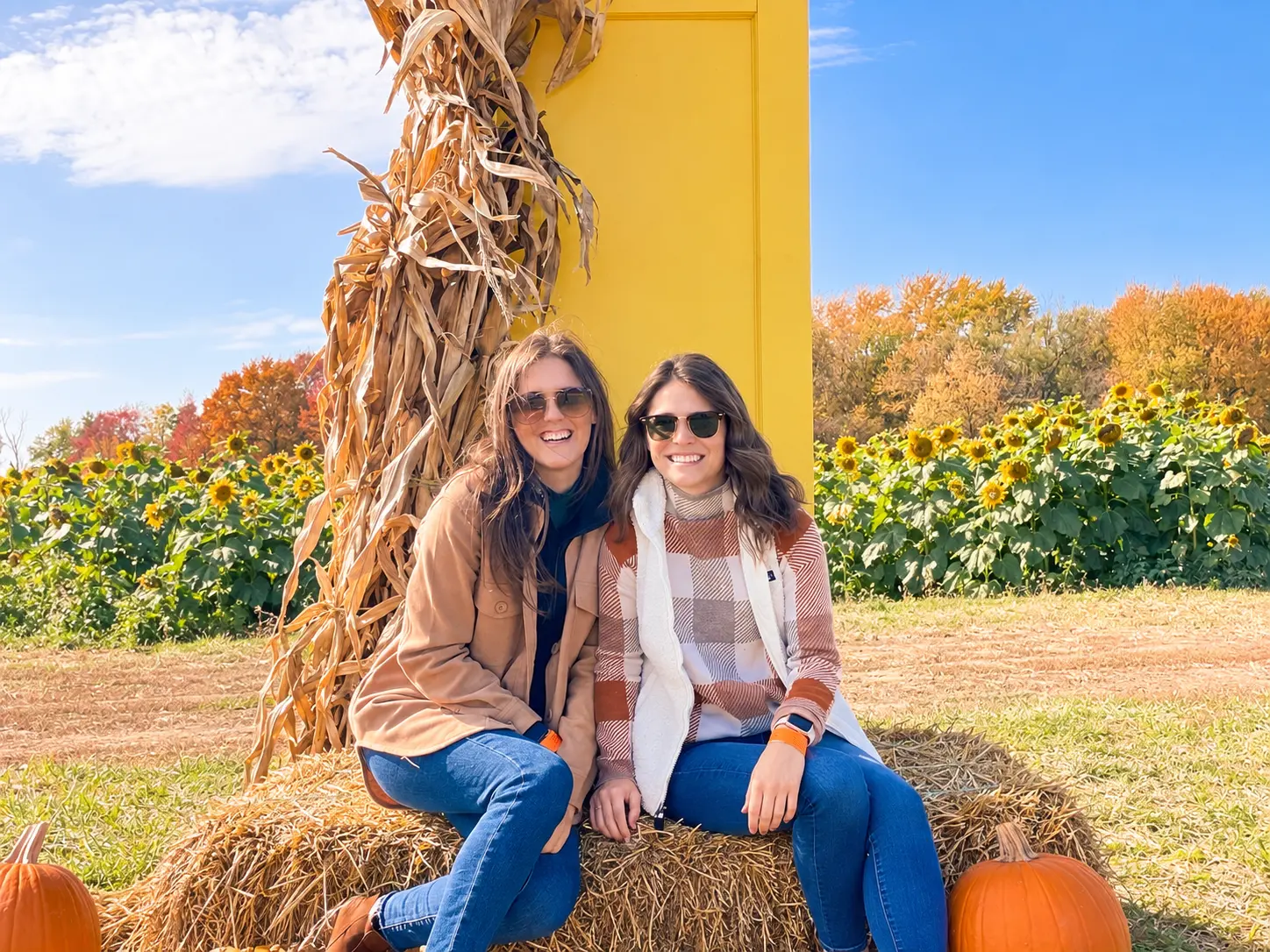 The two Honeygirls sisters smiling together at a sunflower farm in autumn